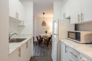 モントリオールにあるCozy 1BR on Rene-Levesqueの冷蔵庫と椅子付きのテーブルがあるキッチン