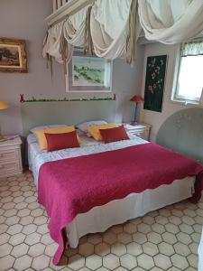 a bedroom with a large bed with red and yellow pillows at Le Mazet du Lapin Rouge in Figanières
