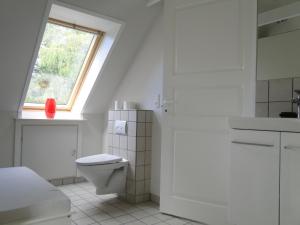 a white bathroom with a toilet and a window at Dyssegaard B&B in Skallerup