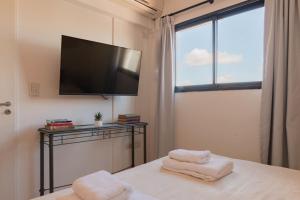 a bedroom with a tv and a bed with towels at Fliphaus Ravignani 1200 - Lux 1 Bd Pool Palermo Hollywood in Buenos Aires