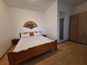 a bedroom with a wooden bed with white sheets at Casa Nicolas in Costinesti