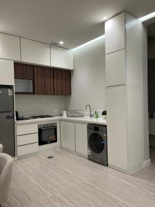 a kitchen with white cabinets and a sink and a dishwasher at فيلا سورا 2 in Buraydah