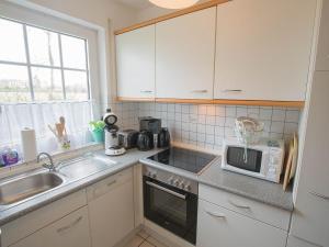 une cuisine avec un évier et un micro-ondes dans l'établissement Ferienhaus Heineke, FeWo Vermittlung Nordsee, à Dangast