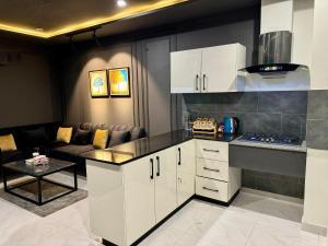 a kitchen with white cabinets and a living room at AirHomes By Zameen Opal in Lahore