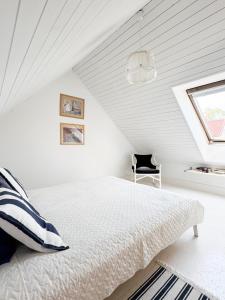a white bedroom with a bed and a chair at Cardinalis house in Pāvilosta
