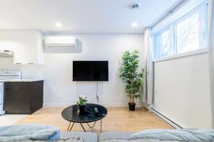 ein Wohnzimmer mit einem Tisch und einem TV an der Wand in der Unterkunft Longueuil New Stylish 3-BDR free parking close to Dix 30&DT in Longueuil