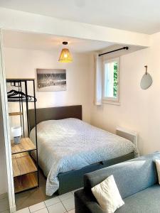 een slaapkamer met een bed en een bank bij La Cabane de Riva Bella in Ouistreham