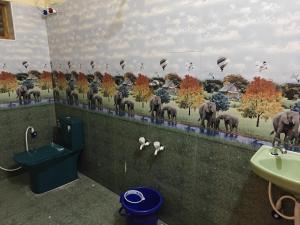 ein Badezimmer mit einem Wandgemälde von Elefanten an der Wand in der Unterkunft Malathi Residency in Arumuganeri