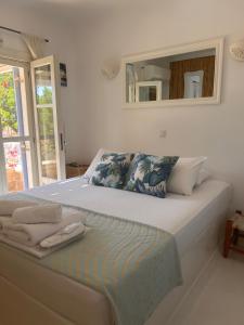 a white bedroom with a large bed with a mirror at Simos suites in Elafonisos
