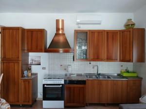a kitchen with wooden cabinets and a stove and a sink at La Casa Del Nonno in Ischitella