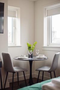 a dining room table with two chairs and a vase with plants at The Bramble at The Balfour by Coorie Doon Stays in Milton of Balgonie