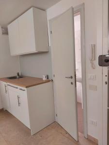 a kitchen with white cabinets and a sink and a door at Petit Biscuit - Wi-Fi - Kitchen - AC - Parking in Lido di Camaiore