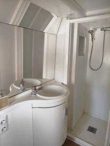 a white bathroom with a sink and a shower at Caravana en la huerta in Tiñosa Alta
