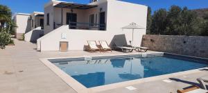 a villa with a swimming pool in front of a house at Sirines Apartments in Palekastron