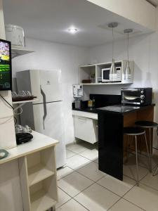 a kitchen with a black counter and a white refrigerator at Aldeia das Águas Village Flat Térreo in Barra do Piraí +25 photos