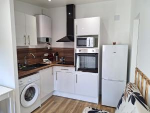a white kitchen with a refrigerator and a microwave at Maisonnette 4 pers - Terrasse - Olivet in Olivet