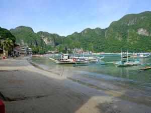a group of boats docked on the shore of a beach at Cabugao Lodge in El Nido