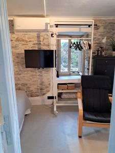 a living room with a tv and a chair at Akros-cottage on mountain- ground floor in Stavrinídes