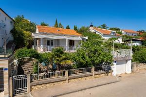 a white house with an iron fence and trees at MY DALMATIA - Vacation house Maslenica with sea view terrace in Šarić