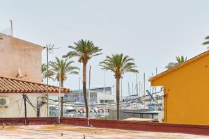 a marina with palm trees and a yellow building at Beachside Bliss in Caleta De Velez