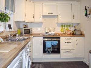 une cuisine avec des armoires blanches et un lave-vaisselle noir dans l'établissement Mountain View, à Blaenau Ffestiniog