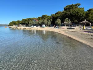 a beach with a group of people sitting under umbrellas at BARKA House Pakoštane in Pakoštane +5 photos