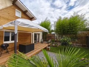 a patio with an umbrella on a wooden deck at Maison duplex Bisca avec jardin in Biscarrosse