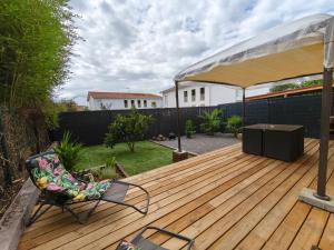 a wooden deck with a tent and a chair at Maison duplex Bisca avec jardin in Biscarrosse +11 photos