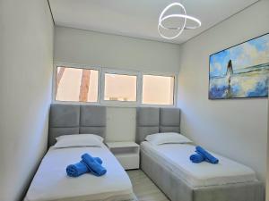 two beds in a room with blue towels on them at Holiday Apartment in San Pietro Residence 304 in Lalzit Bay