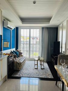 un salon avec un canapé et une grande fenêtre dans l'établissement Grand Florida Beachfront Pattaya, à Na Jomtien