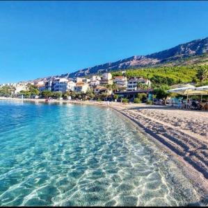 a beach with a group of buildings and the water at Suzy apartment, Dugi Rat in Dugi Rat