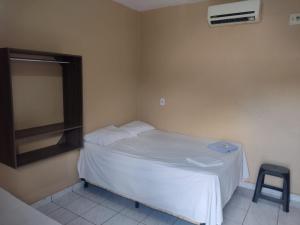 a small bedroom with a white bed and a stool at Hotel Avenida in Acailandia