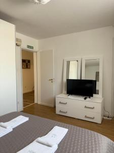 a white bedroom with a bed and a dresser with a mirror at Casa do Albano in Viana do Castelo
