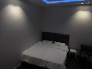 a bedroom with a bed with white sheets and a blue light at استديو 1 in Jeddah