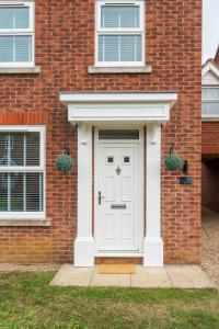 a white front door of a brick house at Falcon Cottage in Sleaford