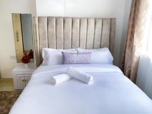 a white bed with two rolled towels on it at 1 Bedroom Apartment, Garden Estate,Nairobi in Nairobi
