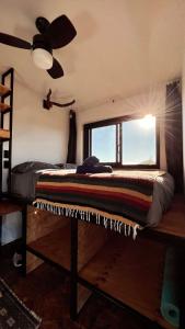 a bedroom with a bed with a window and a ceiling fan at Libra Eco-Adventure Hostel in El Pescadero