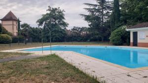 a swimming pool in front of a building with a tower at Appartement cosy in Cugnaux