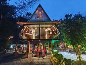 a house with a deck with tables and chairs at River Valley Huts, Wayanad in Panamaram