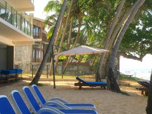 a group of blue chairs and an umbrella on the beach at Sayura Beach Hotel in Unawatuna