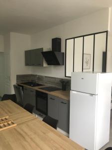 a kitchen with a white refrigerator and a table at appt 10 couchages tt confort appt 3 in Laveissière