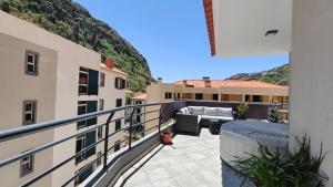 a balcony with a couch and chairs on a building at Apartamento Luar in Ribeira Brava