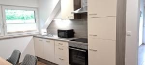 a kitchen with white cabinets and a sink and a microwave at Apartmaji Božiček Olimje in Podčetrtek +20 photos