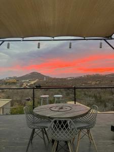a table and chairs on a balcony with a sunset at Libra Eco-Adventure Hostel in El Pescadero +26 photos