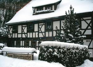 a snow covered house with a christmas tree in front of it at Hotel Zum Bürgergarten in Stolberg i. Harz