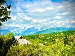 a barn on a hill with mountains in the background at Koča Velika Planina - Chalet Kamrica in Stahovica +13 photos