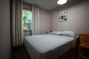 卡灵港Lake Muskoka Deluxe 2-bdrm Cottage - Pier 100 #60的一间卧室，里面有一张床和一扇窗户。