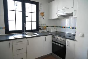 a kitchen with white cabinets and a sink and a window at Blue Surf House Only surf in Corralejo
