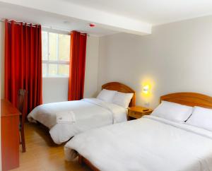 1 dormitorio con 2 camas y una ventana con cortinas rojas en Hotel Centro Huancayo, en San Antonio