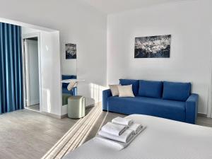 a living room with a blue couch and a bed at Dine Hotel in Ksamil
